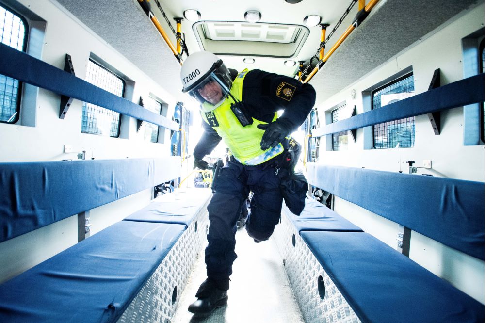 En polis springer in i den säkrade bussen mellan sätena. Foto.