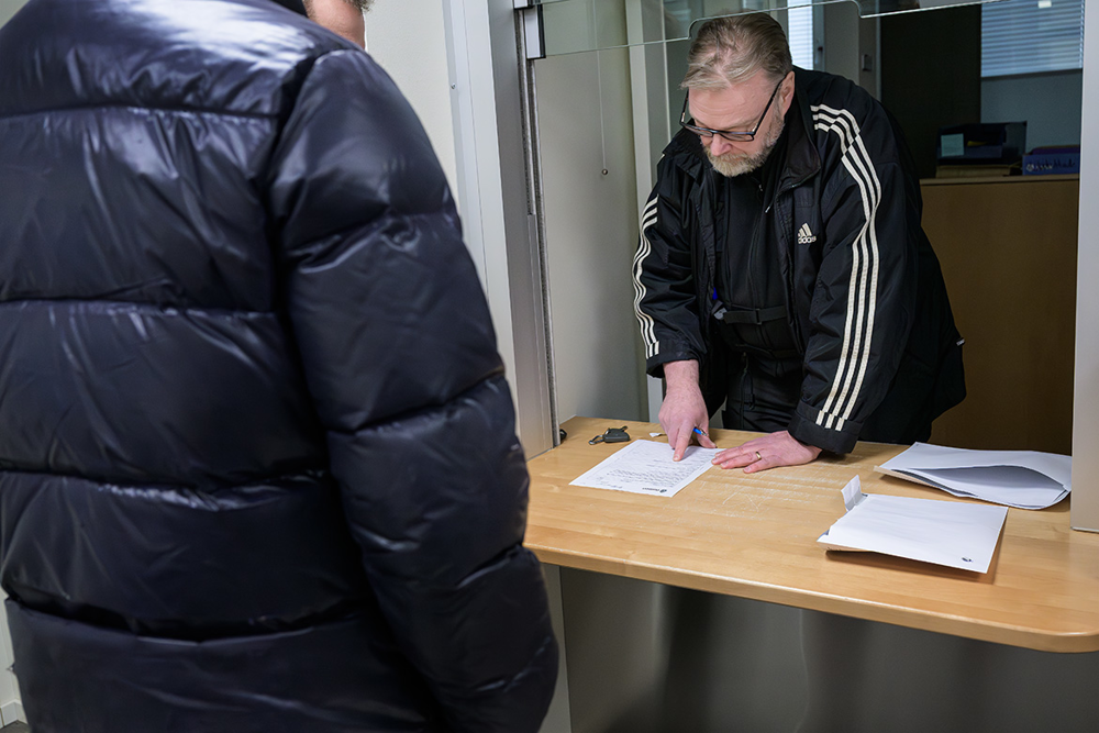 Martin Asplund står i en receptionslucka på polisstationen och pratar med en kille i täckjacka. Foto.