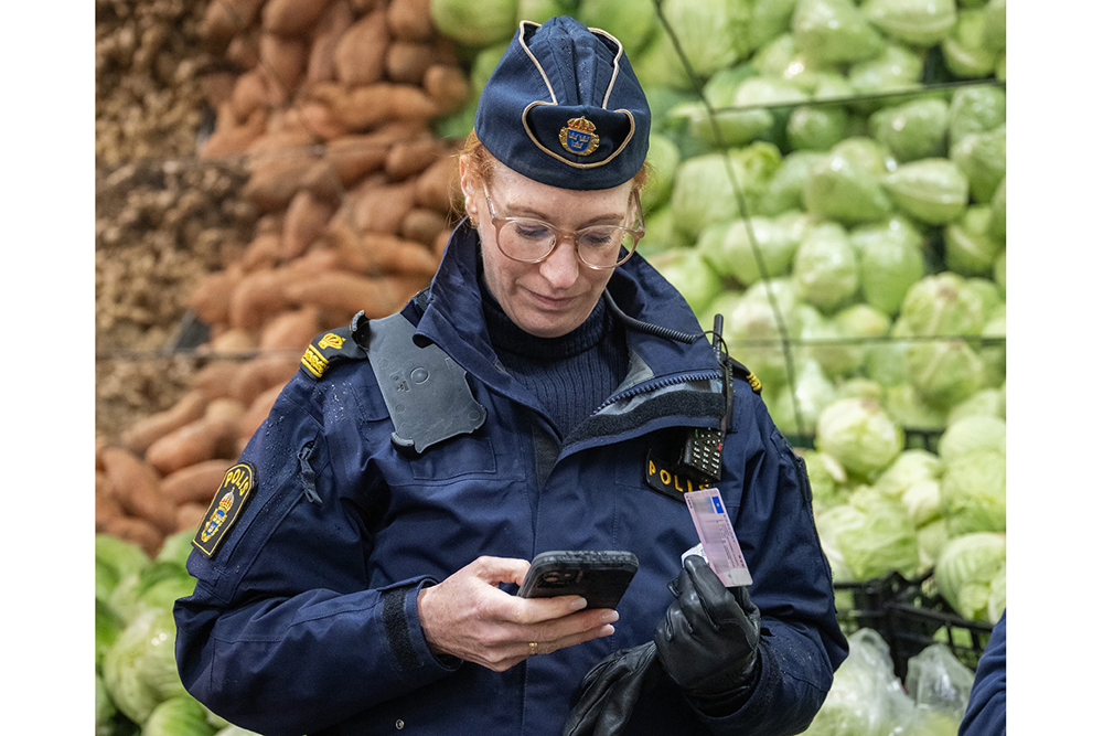 Polisen Jenny Thronell står vid salladshuvuden och slår i mobiltelefonen. Foto.