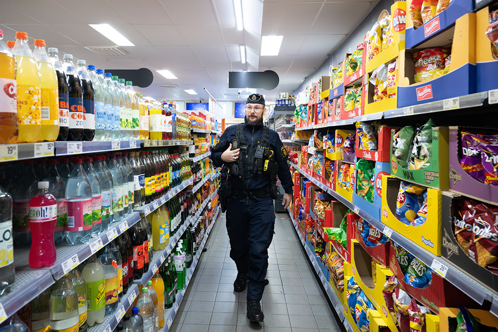Gränspolisen Olof Magnusson går i en gång mellan chips och snacks på ena sidan och läsk och saft på den andra. Foto.