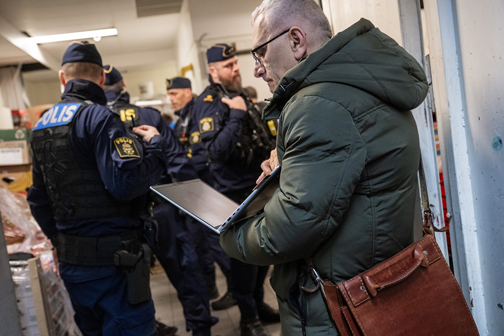 Poliser och inspektörer från andra myndigheter pratar med personal inne på lagret. Foto.