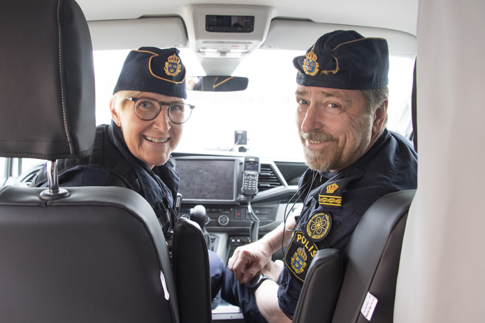 Elisabeth ”Bettan” Samuelsson och Mikael Finsberg sitter i en polisbil tillsammans och tittar bak mot baksätet. Foto.