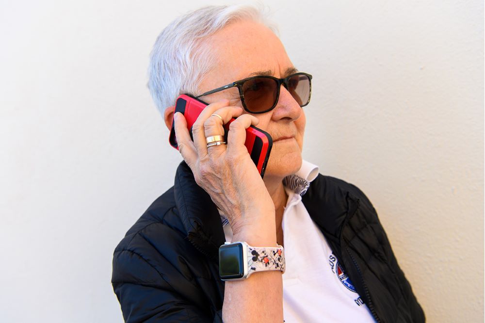 En äldre dam pratar i mobiltelefon. Foto.
