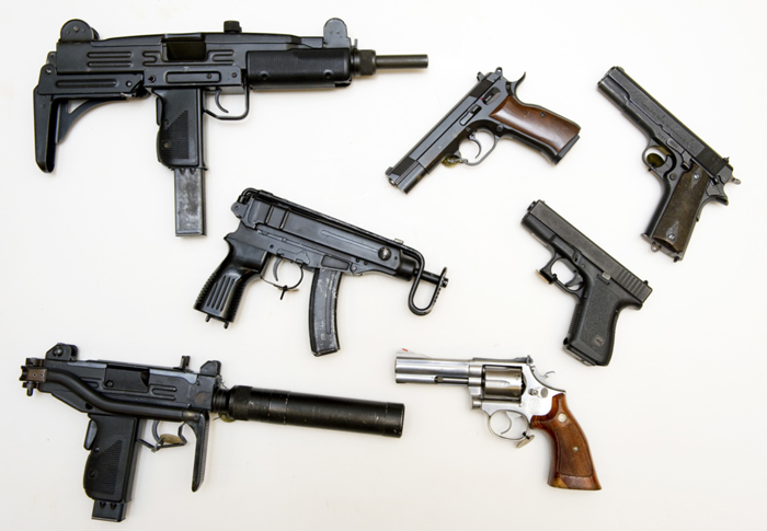En samling vapen som tagits i beslag, utspridda på ett bord. Foto.