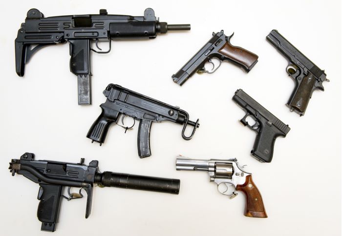 En samling vapen som tagits i beslag, utspridda på ett bord. Foto.