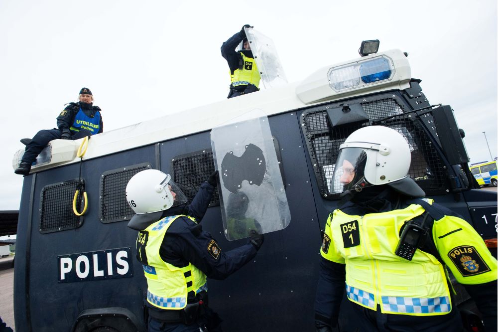 Flera poliser övar på att ta sig ur de säkrade mörkblå polisbussen. Foto.