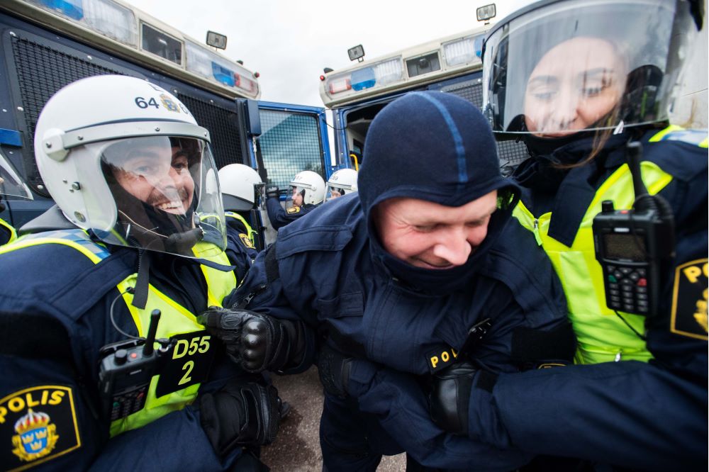 En polis som spelar demonstrant tas omhand av två poliser. Foto.