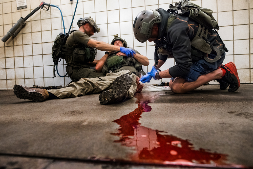 Två insatspoliser gör första hjälpen på en skadad kollega som blöder från benen under en övning.