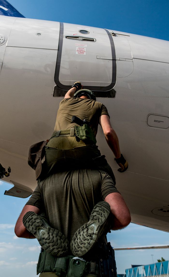 En operatör sitter på en annans axlar för att lyfta upp honom till ett flygplan.