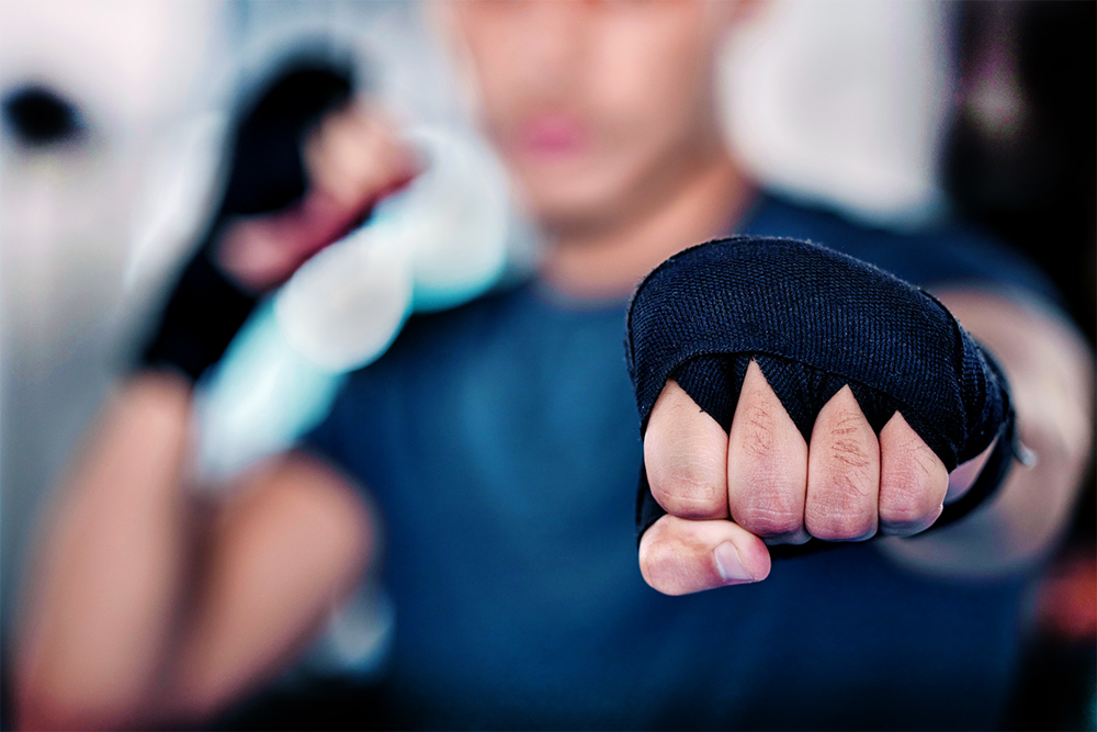 En knuten hand i ett slag framåt av en kille med svarta handskar på sig. Foto.