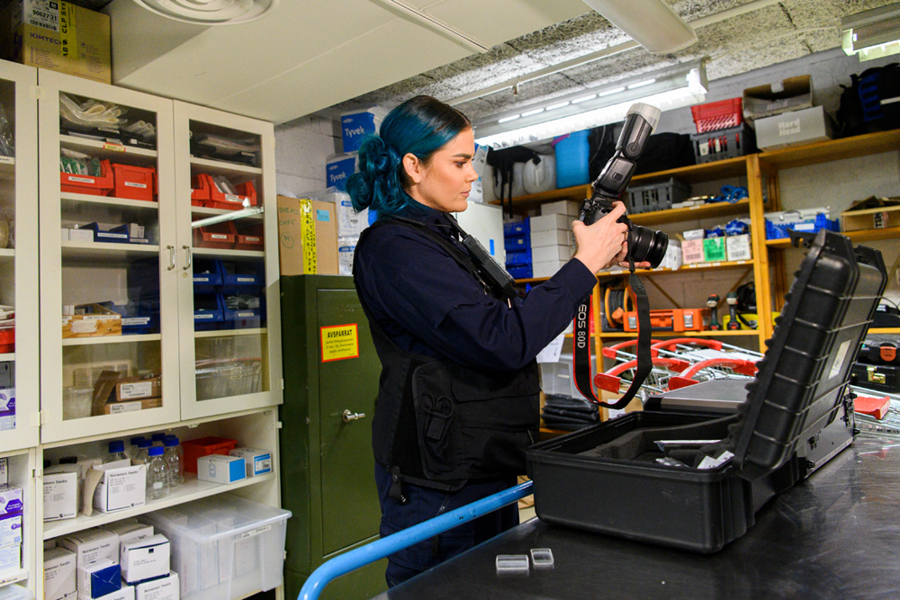 Kelda Stagg står i ett förråd och packar väskan med utrustning som behövs vid en platsundersökning. Foto.