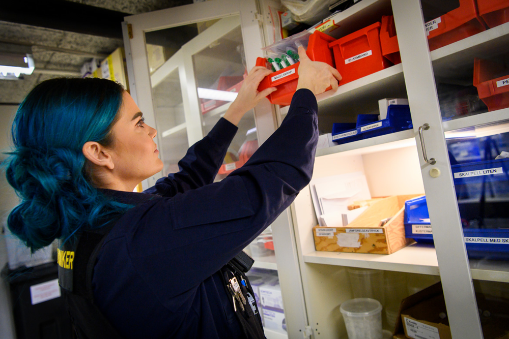 Kelda Stagg plockar ner en låda med utrustning från en hylla. Foto.