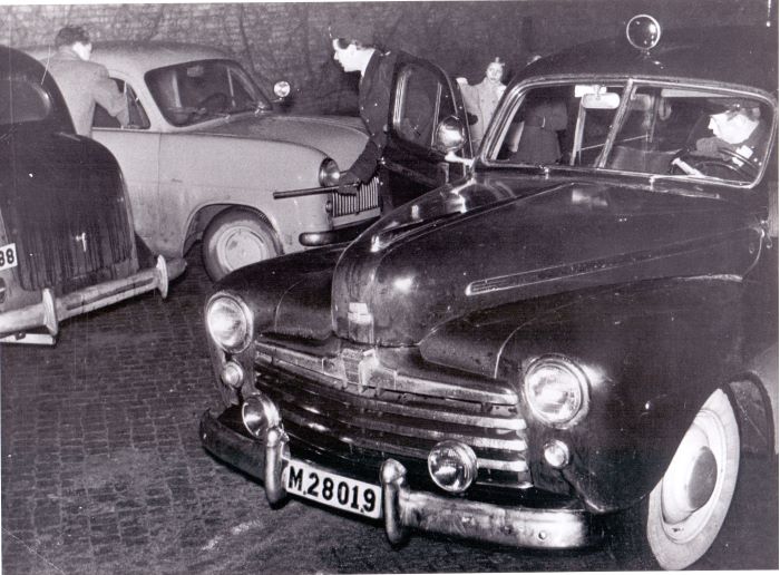 En radiopolis med batong rusar ut ur en radiobil från 1950-talet. Foto.