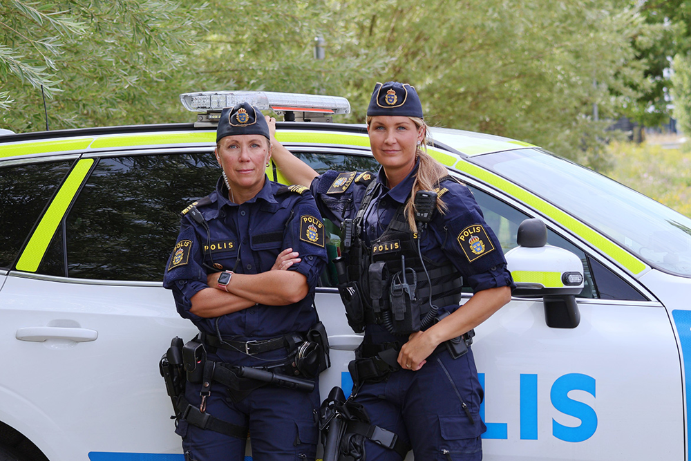 Poliserna Maja Eriksson och Sofie Zarouk står framför en polisbil. Foto.