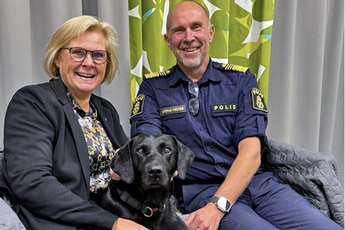 Petra Lundh och Stefan Hector med en svart labrador mellan sig i en soffa. Foto.