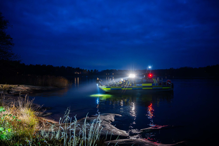 Sjöpolisens båt närmar sig land i mörkret för att lasta av. Foto.