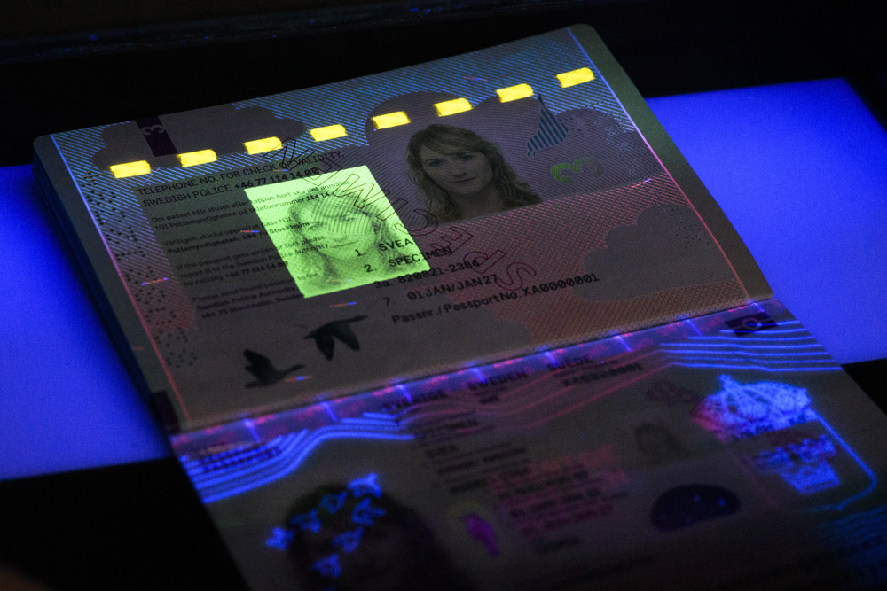 Passets insida belyst med ultraviolett ljus så att en extra bild på innehavaren framträder. Foto.