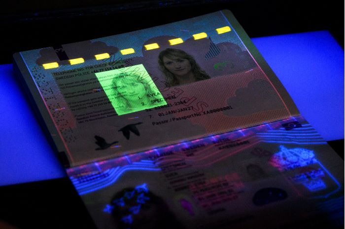 Passets insida belyst med ultraviolett ljus så att en extra bild på innehavaren framträder. Foto.