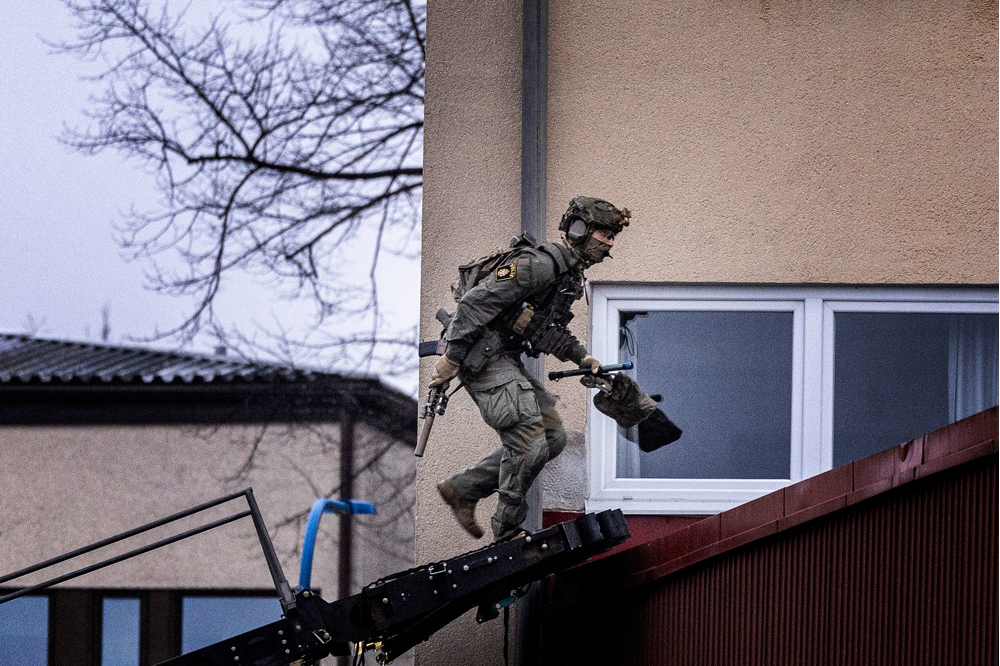 En NI-operatör ses gå över takpannorna för att ta sig till fönstret på den misstänkte gärningspersonens bostad.