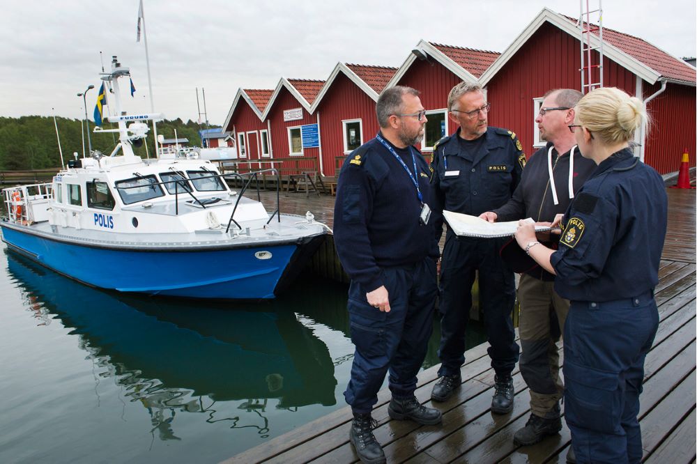 Thomas Andersson samtalar med tre uniformerade poliskollegor på båtbryggan.