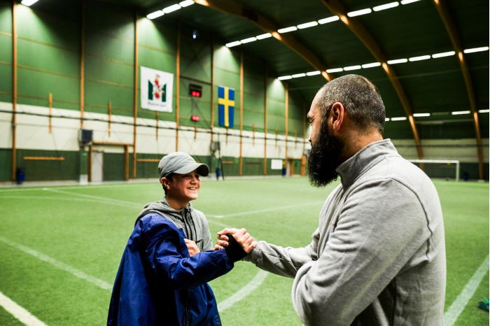 Gorgin Shoai och sjundeklassaren Amis Nouhi står på fotbollsplanen och gör ett handslag med varandra.