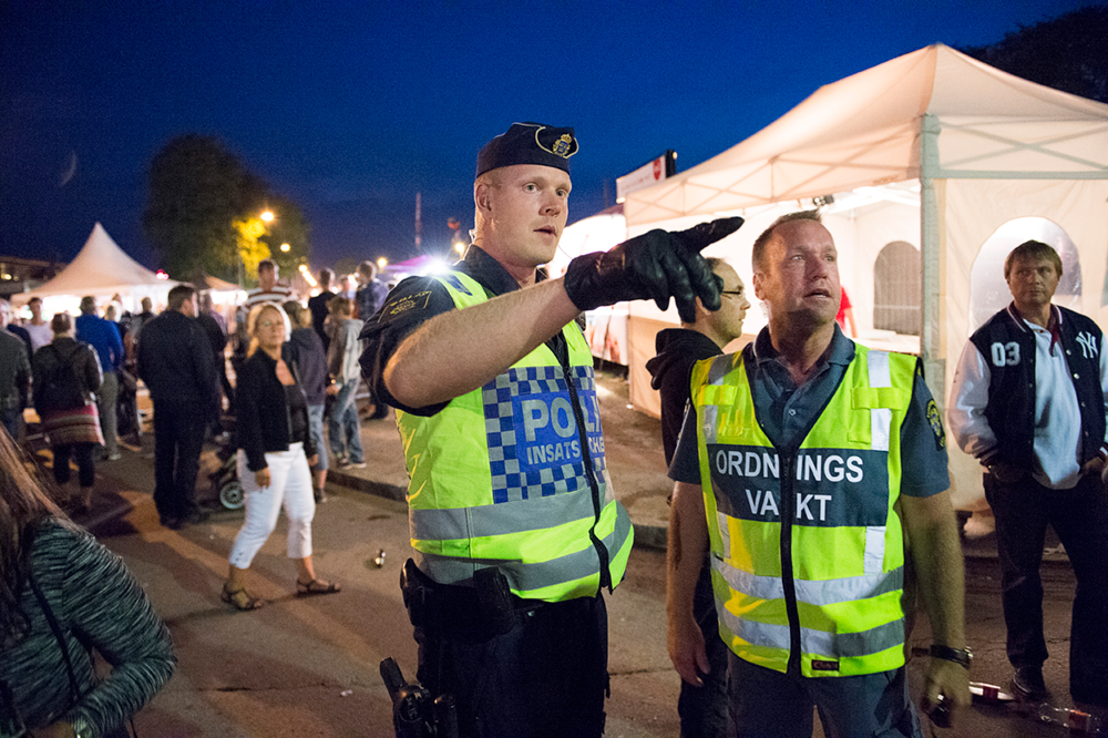 En insatschefen från polisen och en ordningsvakt går igenom läget under ett event utomhus. Foto.