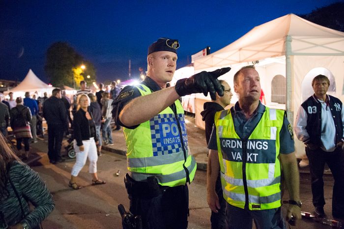 En insatschefen från polisen och en ordningsvakt går igenom läget under ett event utomhus. Foto.