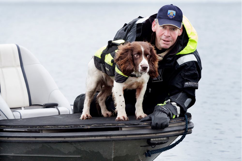 Polishunden Ben och hundföraren Johan Esbjörnsson, i fören på en båt.