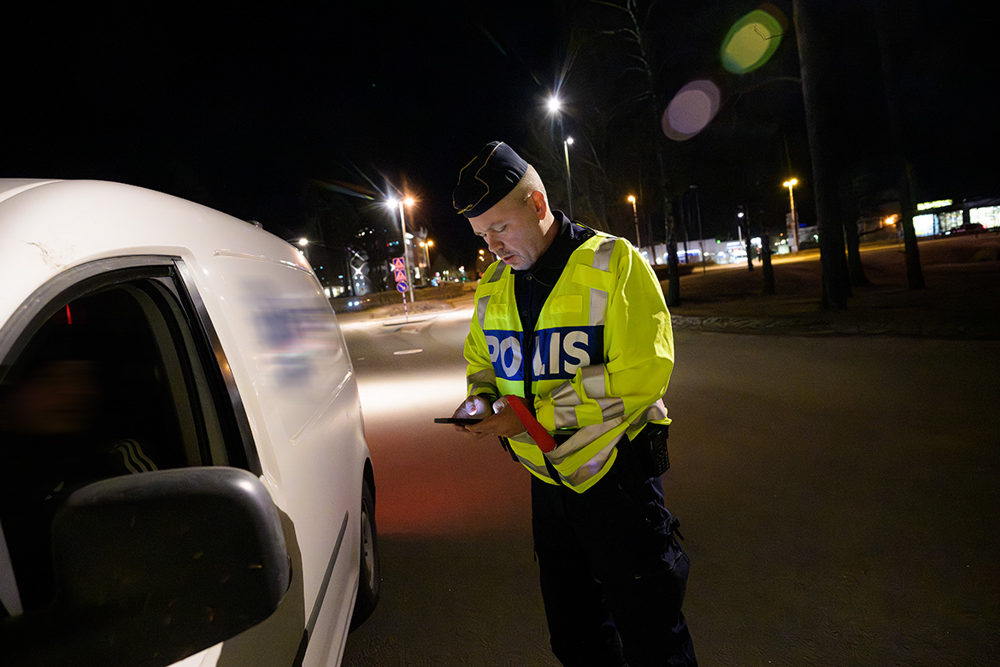 Niklas Wilson står vid en vit bil och kollar nykterhet och körkort. Foto.