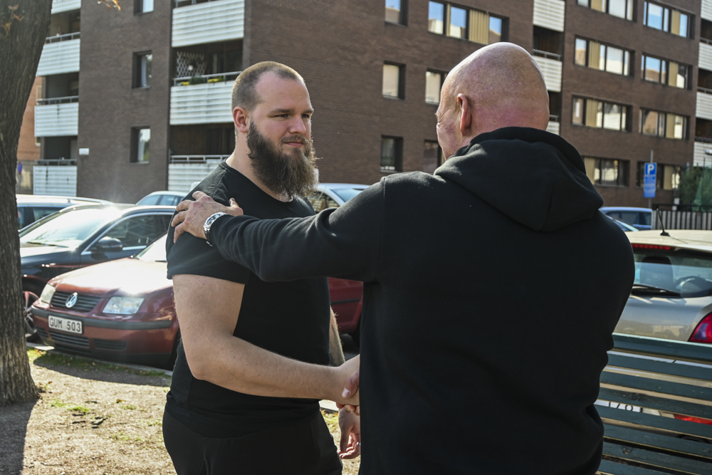 Förhandlaren Kent tar i hand med figuranten och lägger en hand på hans axel. Foto.
