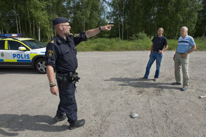 Yttre befälet Jan Ekholm står på en grusplan och pekar mot någonting. I bakgrunden står Tord Tallmarker och Sune Nordh.