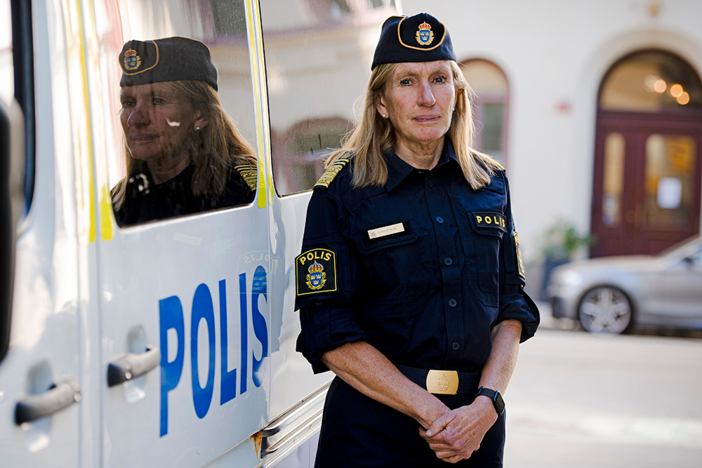 Carin Götblad står bredvid en polisbil och hennes spegelbild syns i ena fönstret. Foto.