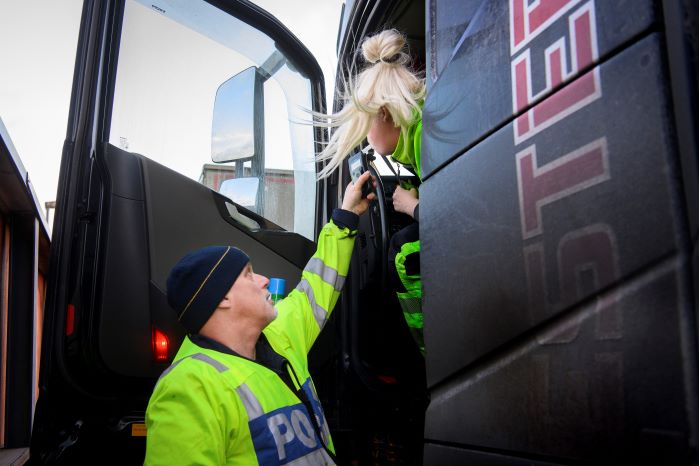 En lastbilschaufför blåser i polisens blåsinstrument för att kolla alkoholpromillehalt. Foto.