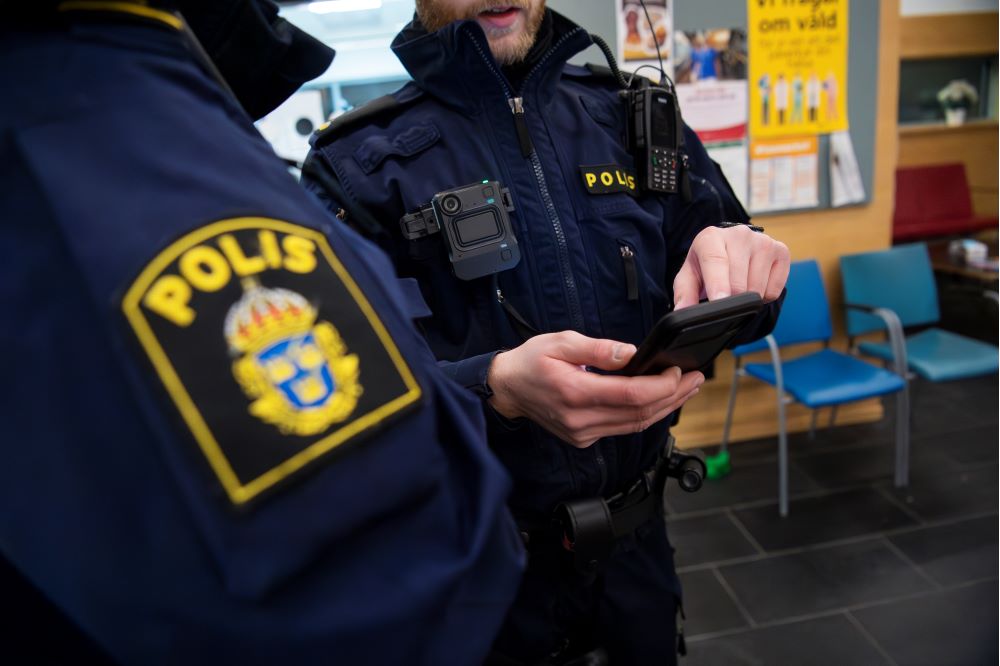 En polis visar något i mobilen för en annan polis. Foto.