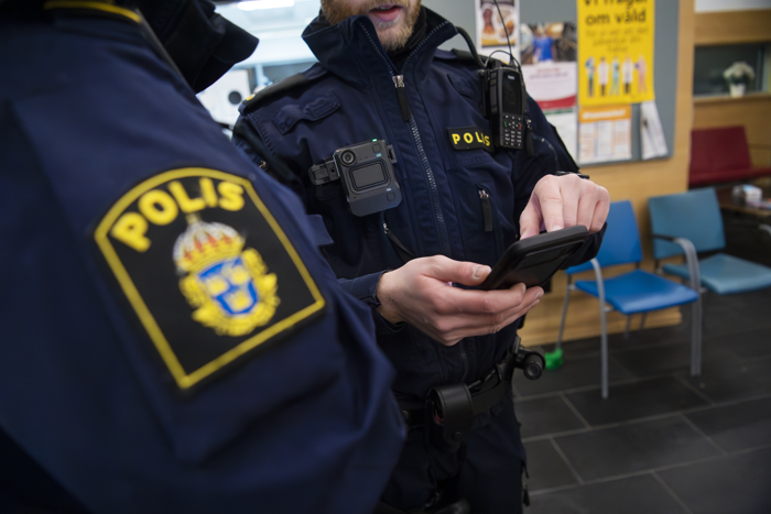En polis visar något i mobilen för en annan polis. Foto.