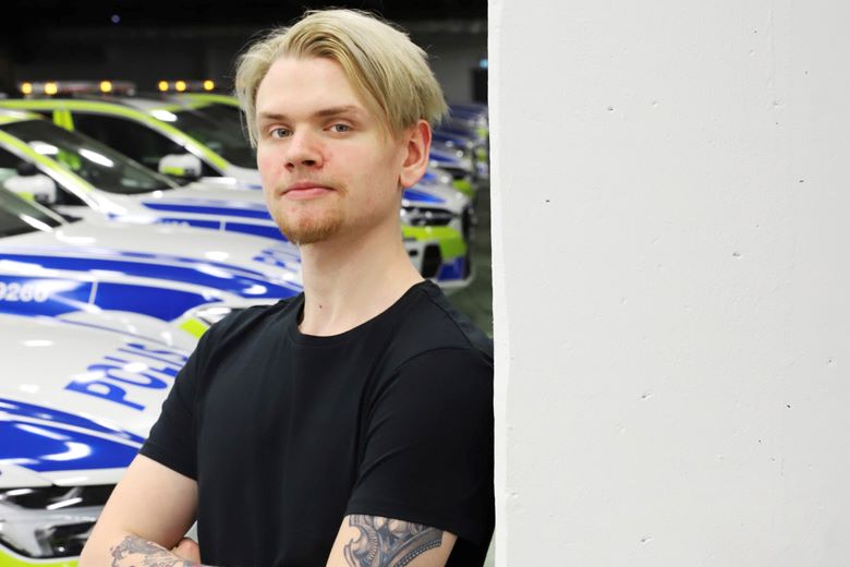 Carl Gustafsson står framför en rad med polisbilar i ett garage. Foto.