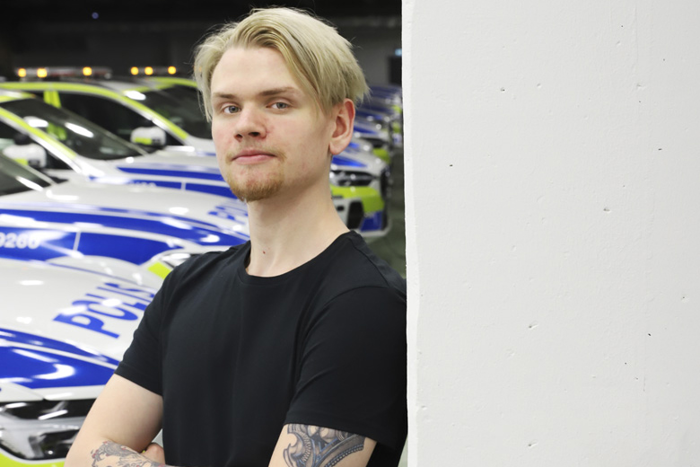 Carl Gustafsson står framför en rad med polisbilar i ett garage. Foto.