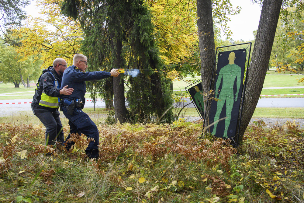 Instruktör Steve Belshaw står bakom en kursdeltagare som avfyrar elchockvapnet mot en måltavla i papp. Foto.