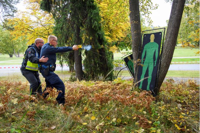 Instruktör Steve Belshaw står bakom en kursdeltagare som avfyrar elchockvapnet mot en måltavla i papp. Foto.