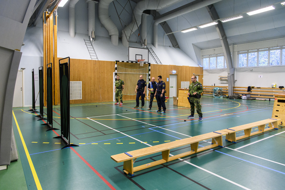Instruktör Steve Belshaw står med några kursdeltagare i en idrottshall. Foto.