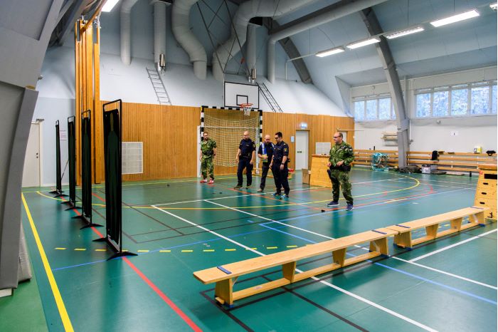 Instruktör Steve Belshaw står med några kursdeltagare i en idrottshall. Foto.