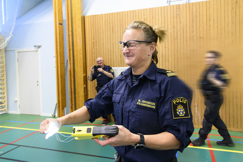 Utbildningssamordnare Magdalena Johansson håller i de strömförande trådarna från sitt elchockvapen. Foto.
