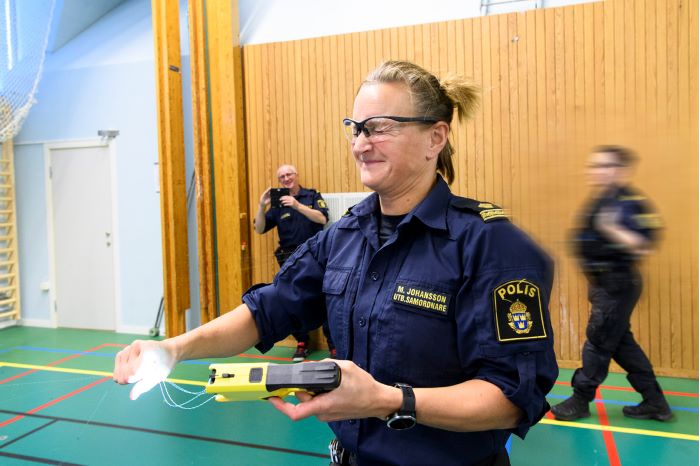 Utbildningssamordnare Magdalena Johansson håller i de strömförande trådarna från sitt elchockvapen. Foto.