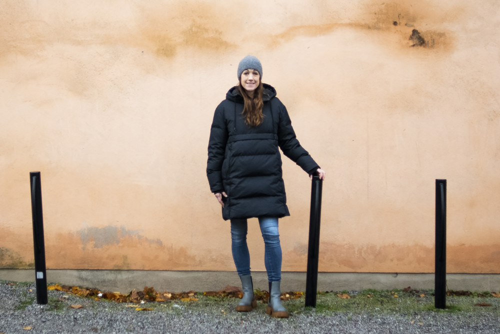 Jenny Edin står utomhus framför en husfasad. Foto.