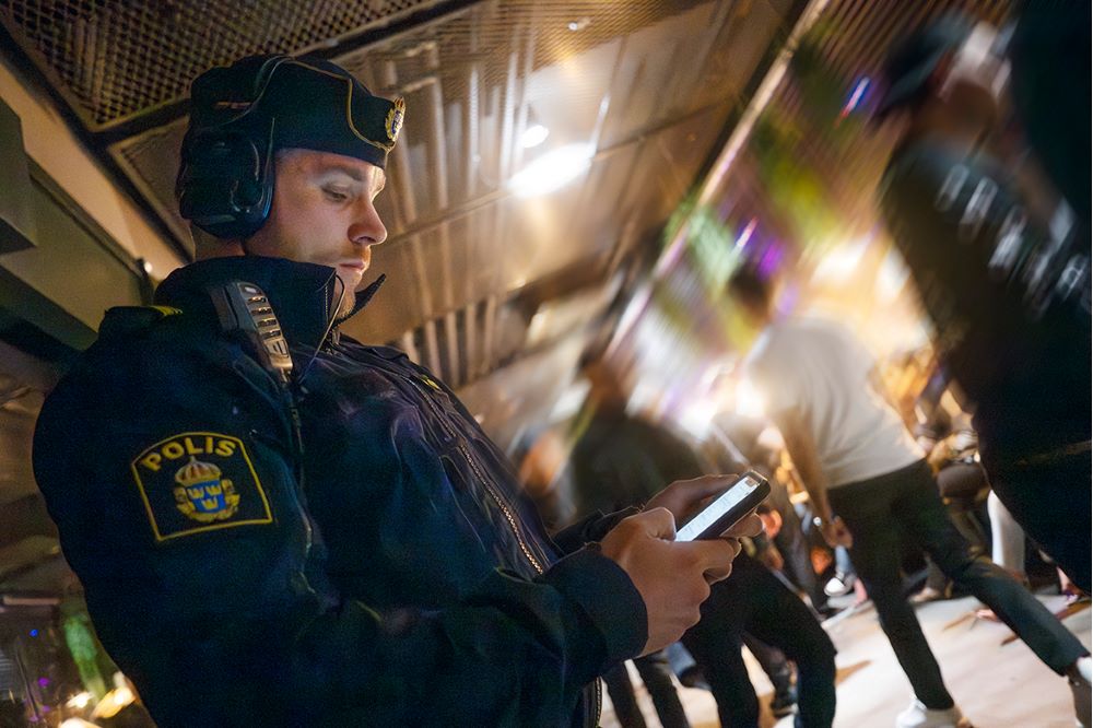 Mattias Brunn står med hörselkåpor på och skriver i sin mobil. Foto.
