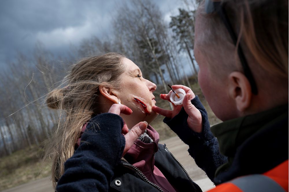 En figurant får en knivskada sminkad på kinden. Foto.