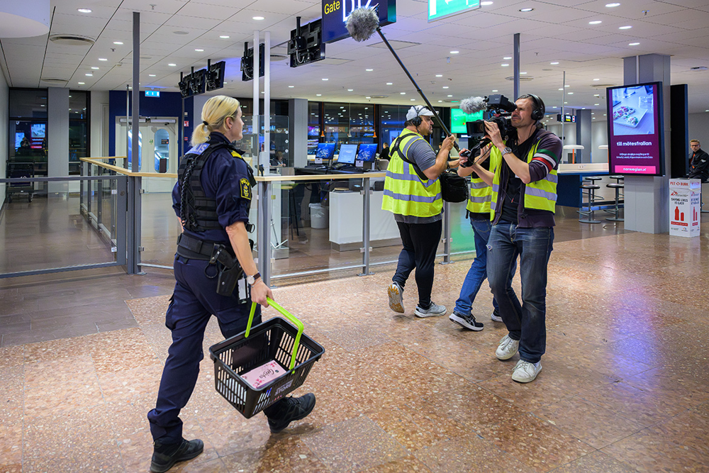 Lina går mot filmteamet med en varukorg i handen. Foto.