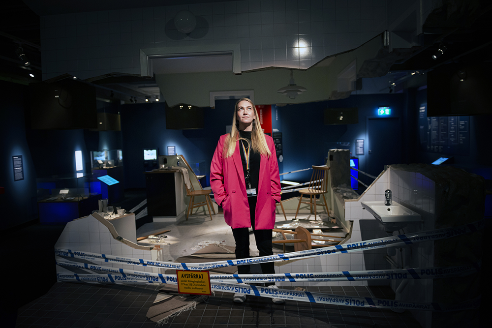 Pedagogen Maria Blonde Andersson står mitt i utställningen för en brottsplats. Foto.