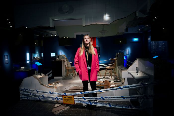 Pedagogen Maria Blonde Andersson står mitt i utställningen för en brottsplats. Foto.