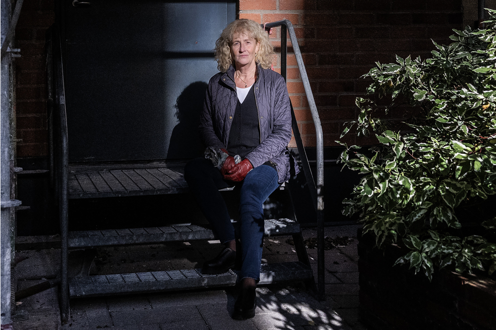 Cecilia Forzelius sitter på en järntrappa utanför en tegelbyggnad. Foto.